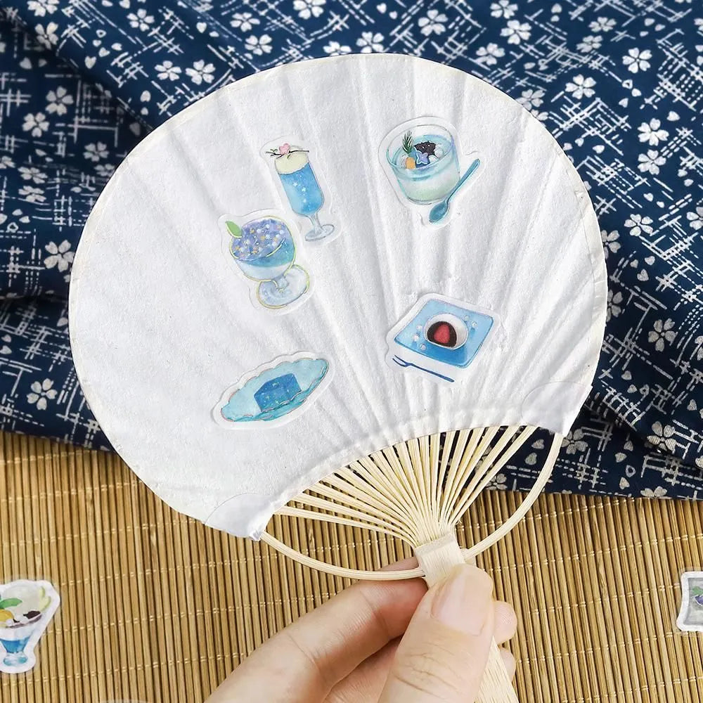 Sheet of blue-themed café flake stickers showing petite plates, parfaits, jelly desserts and drinks with shimmering foil highlights.